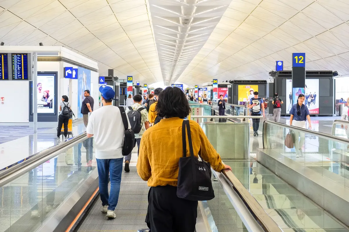 홍콩의 현대적인 공항 터미널을 걷는 승객들의 모습, 여행의 정신을 담고 있다.