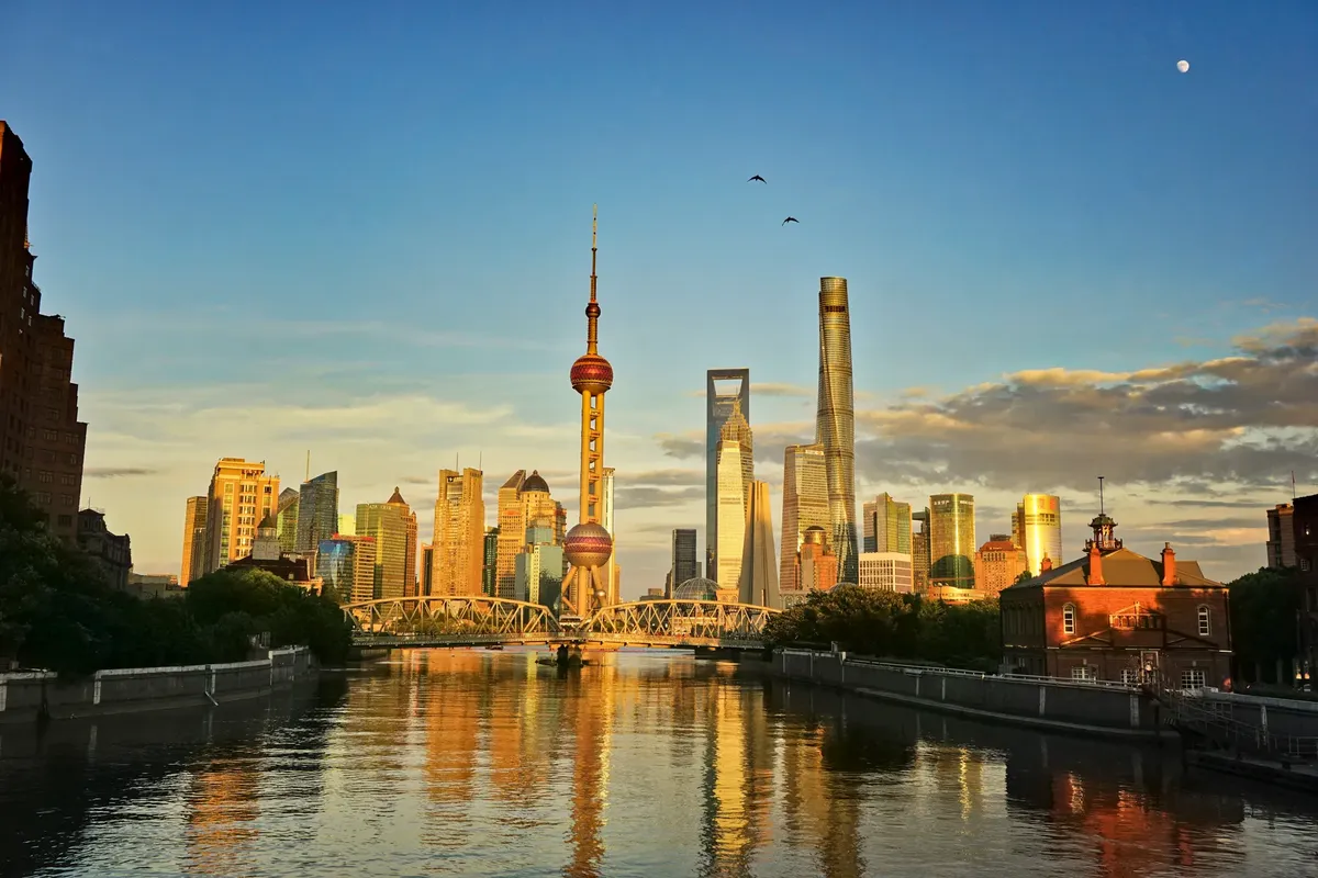 Dramatic view of Shanghai's skyline with the Oriental Pearl Tower and Huangpu River at sunset.