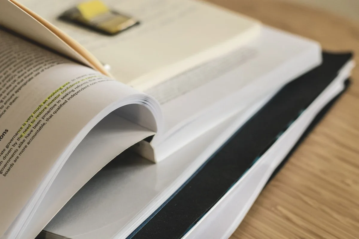 Pile de livres techniques épais et de documents imprimés sur un bureau en bois